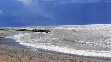 Ein Strand mit Wellen, blauem Himmel und einem Felsen.