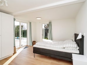 Une chambre à coucher avec un lit, une table de chevet, une lampe et une vue sur l’extérieur.