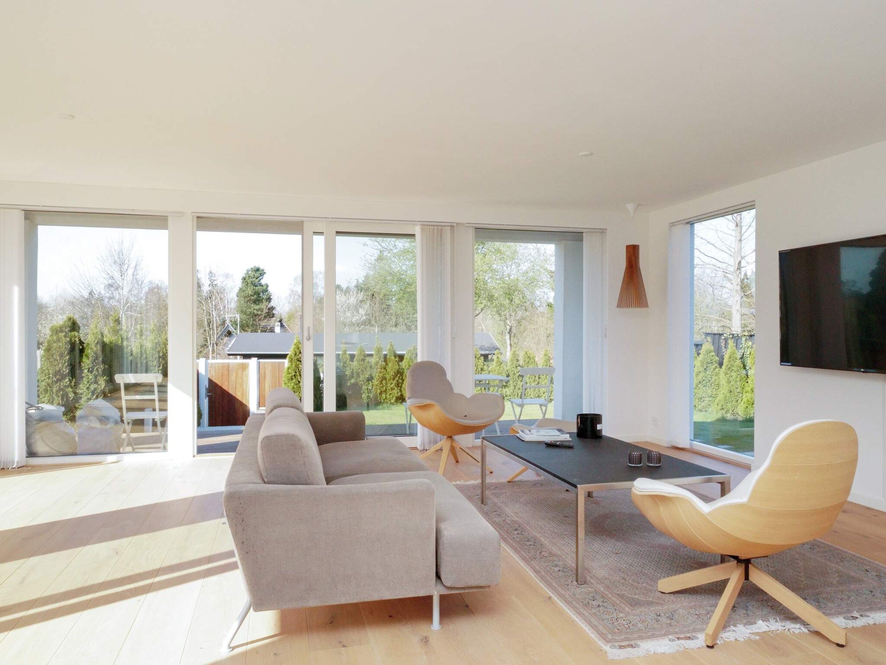 A modern living room with a sofa, two chairs, a coffee table, and a TV mounted on the wall.