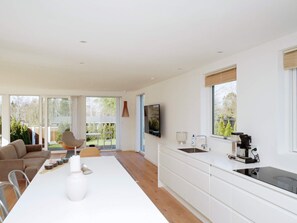 Una cocina moderna con una isla central, una zona de comedor con sofá y sillas, y un televisor montado en la pared.