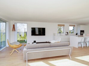 Una sala de estar moderna con un sofá, una televisión y un comedor con sillas.