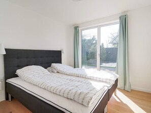 A double bed with a dark headboard in a room with a large window and a view of the outdoors. - 6 Person Holiday Home in Hornbaek (Hornbaek)