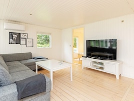 Una sala de estar moderna con un sofá gris, una mesa de centro blanca y un televisor de pantalla plana sobre un mueble blanco.