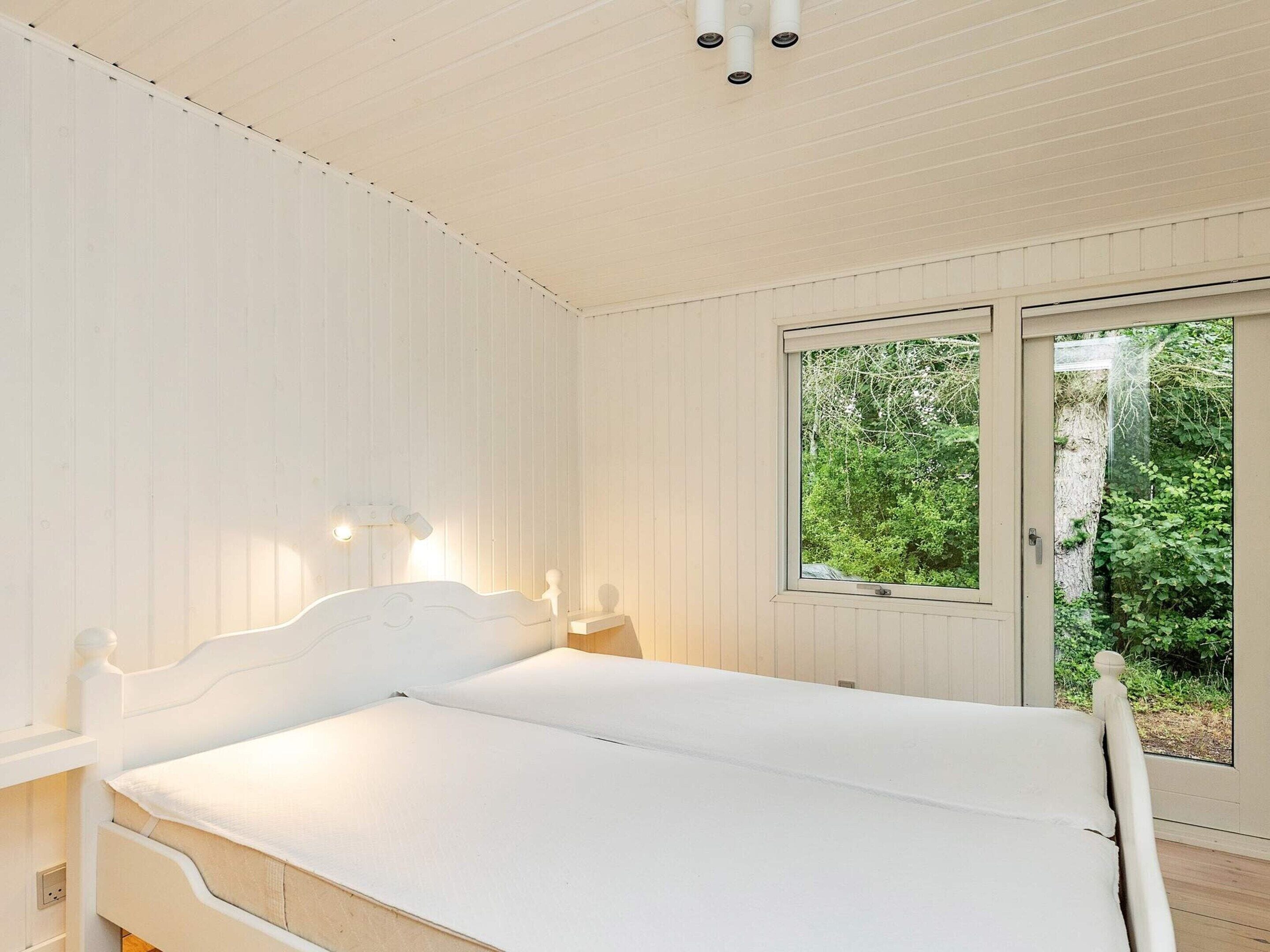 A bedroom with a bed, a window, and a view of greenery.