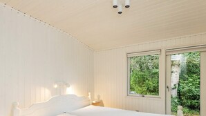 A bedroom with a bed, a window, and a view of greenery.