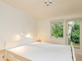 Un dormitorio con cama, ventana y vista a zonas verdes.