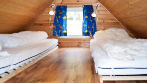A small attic bedroom with two beds, wooden walls, a window with curtains, and a sloped ceiling. - 4 Person Holiday Home in Maloy-by Traum (Kinn)