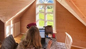 A cozy attic room with a large arched window, wooden walls, and a bed with a polka dot blanket. - 4 Person Holiday Home in Maloy-by Traum (Kinn)