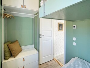 Une pièce avec un banc intégré, une porte, un interrupteur fixé au mur et un petit tableau encadré.