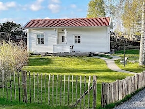 A white house with a red-tiled roof, a front porch, and a well-maintained lawn.