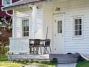 A white house with a covered porch, a door, and a window. - 6 Person Holiday Home in Hoviksnas (Höviksnäs)