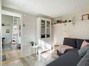 Un salon moderne avec un canapé gris, un meuble blanc aux portes vitrées et une petite table blanche.
