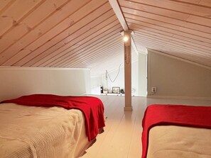 A high-ceilinged attic bedroom with two beds, a white wall, and a visible window. - 6 Person Holiday Home in Hoviksnas (Höviksnäs)