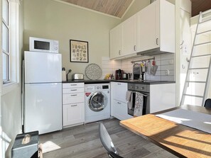 Une cuisine compacte équipée d’un four à micro-ondes, d’un lave-linge et d’un évier.