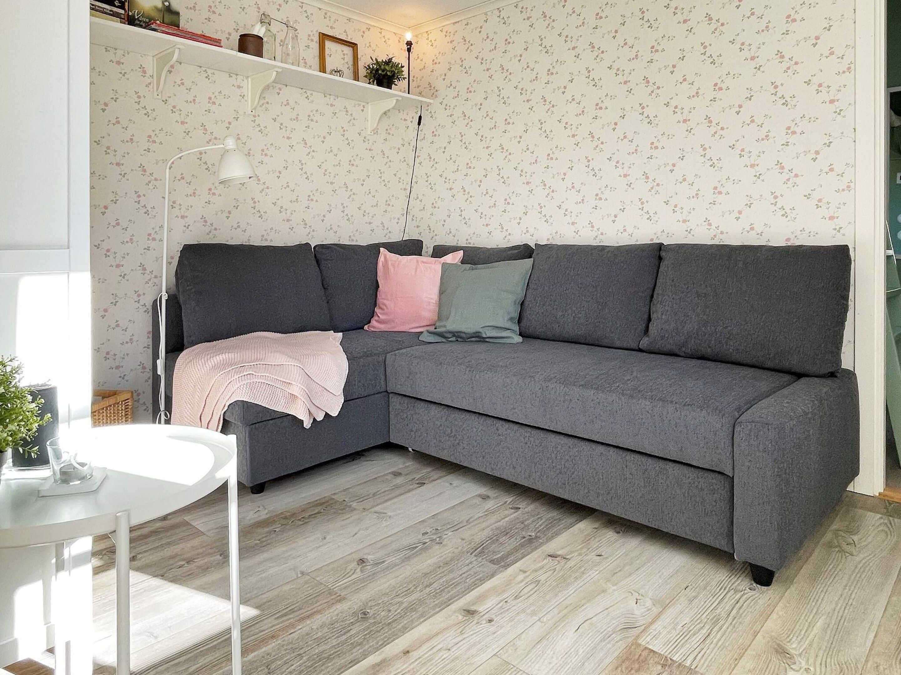 A modern living room with a grey sectional sofa, a white side table, and a wooden floor.