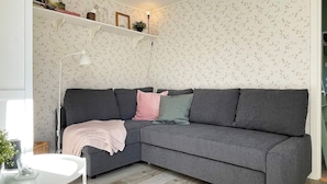A modern living room with a grey sectional sofa, a white side table, and a wooden floor. - 6 Person Holiday Home in Hoviksnas (Höviksnäs)