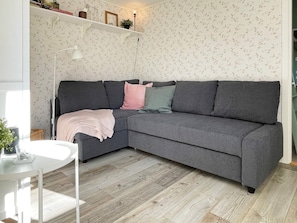 A modern living room with a grey sectional sofa, a white side table, and a wooden floor. - 6 Person Holiday Home in Hoviksnas (Höviksnäs)