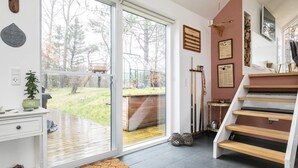 A modern interior with a sliding glass door leading to a garden, a wooden staircase, and a white dresser with a plant. - 6 Person Holiday Home in Hals-by Traum (Hals)