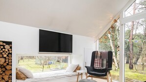 A modern living room with a large window, a flat-screen TV, a cozy seating area, and a wooden floor. - 6 Person Holiday Home in Hals-by Traum (Hals)