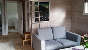 A cozy room with a grey sofa, a wooden ladder, and a painting of a mountainous landscape. - 7 Person Holiday Home in Orsta/brungot (Orsta)