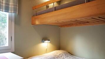A room with a bunk bed, a desk, and a window.