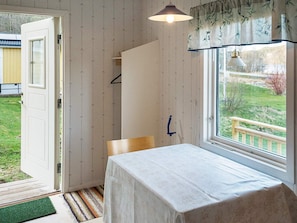 Une pièce comprenant un lit, une table, un luminaire suspendu, une fenêtre donnant sur l’extérieur et une porte menant à l’extérieur.