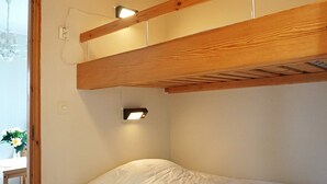 Uma cama de solteiro com cabeceira de madeira e luminária fixada na parede.