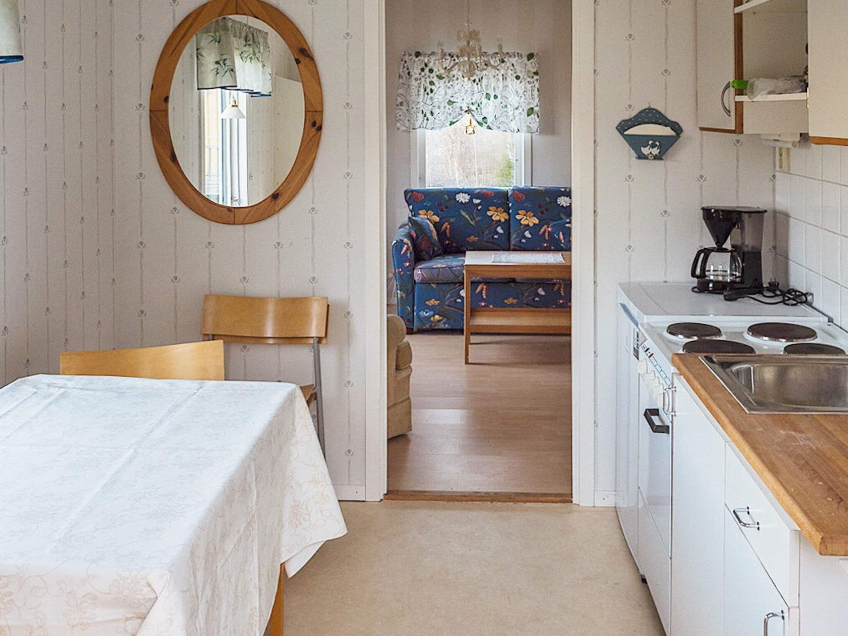 A compact kitchen with a dining area, a sofa, and a wooden table.