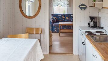 A compact kitchen with a dining area, a sofa, and a wooden table.