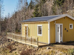 A yellow cabin with a wooden deck, a door, and a window. - 4 Person Holiday Home in Hallevadsholm (Hällevadsholm)