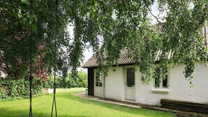 A white house with a small porch, a swing, and a well-maintained lawn.