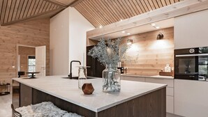 Una cocina moderna con una isla central, techo de madera y electrodomésticos integrados.
