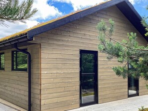 A modern building with horizontal wooden siding, black-framed windows, and a sloped roof. - 5 Star Holiday Home in Hals (Hals)