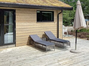 A wooden cabin with two lounge chairs and a patio umbrella.