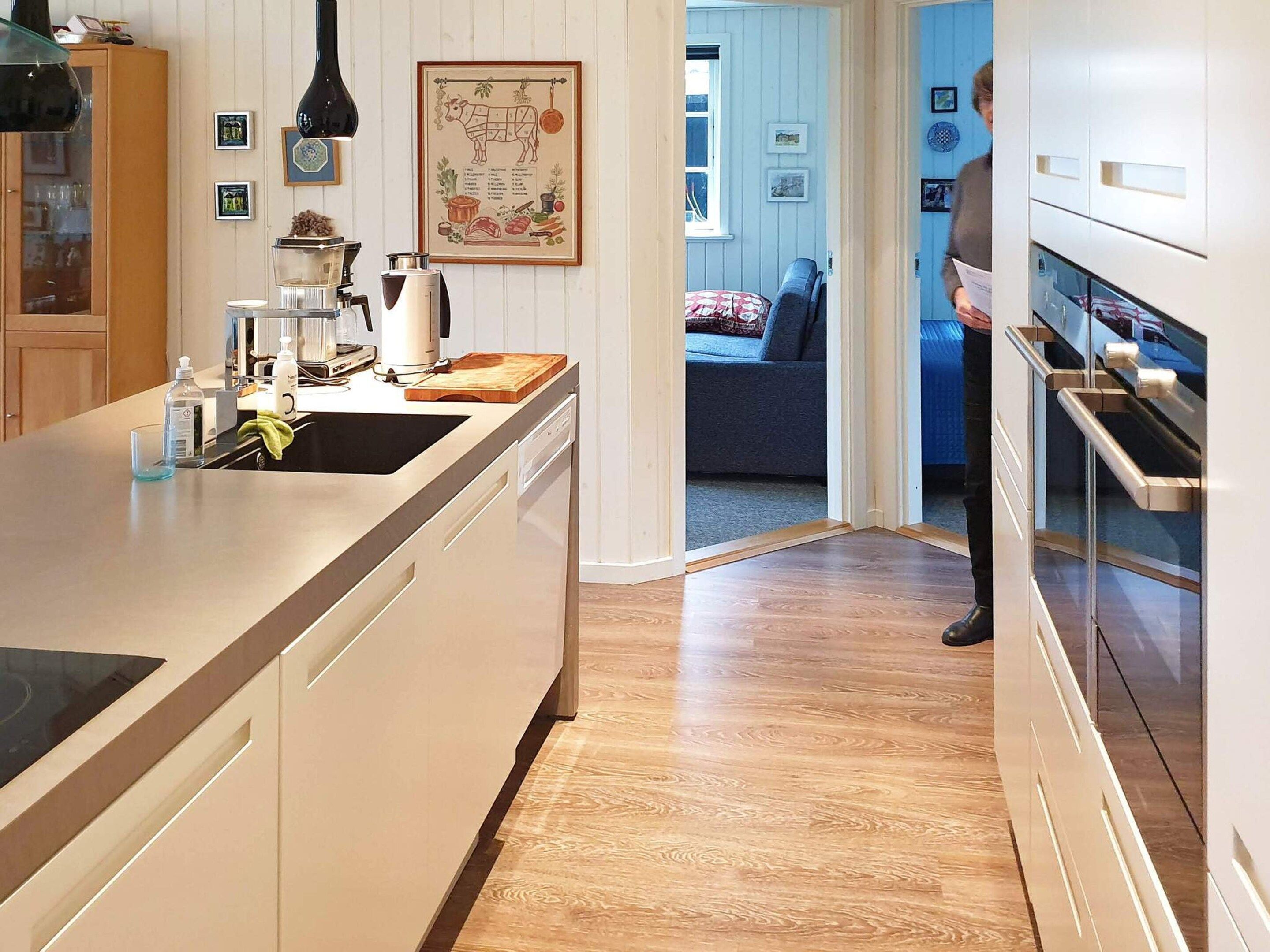 A modern kitchen with a central island, built-in appliances, and a view into the living area.