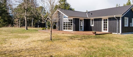 A modern two-story house with a dark exterior, large windows, and a covered patio area.
