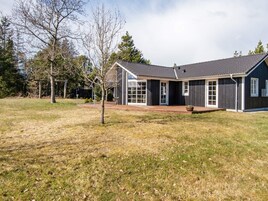 A modern two-story house with a dark exterior, large windows, and a covered patio area.