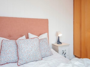A neatly made bed with floral-patterned pillows and a white comforter. - 6 Person Holiday Home in Blavand (Blavand)