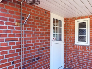 A small, enclosed space with a brick wall, a white door, and a window with a checkered pattern. - 6 Person Holiday Home in Blavand (Blavand)