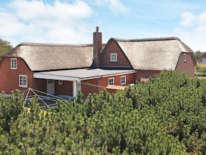 A red brick house with a thatched roof and a chimney. - 6 Person Holiday Home in Blavand (Blavand)