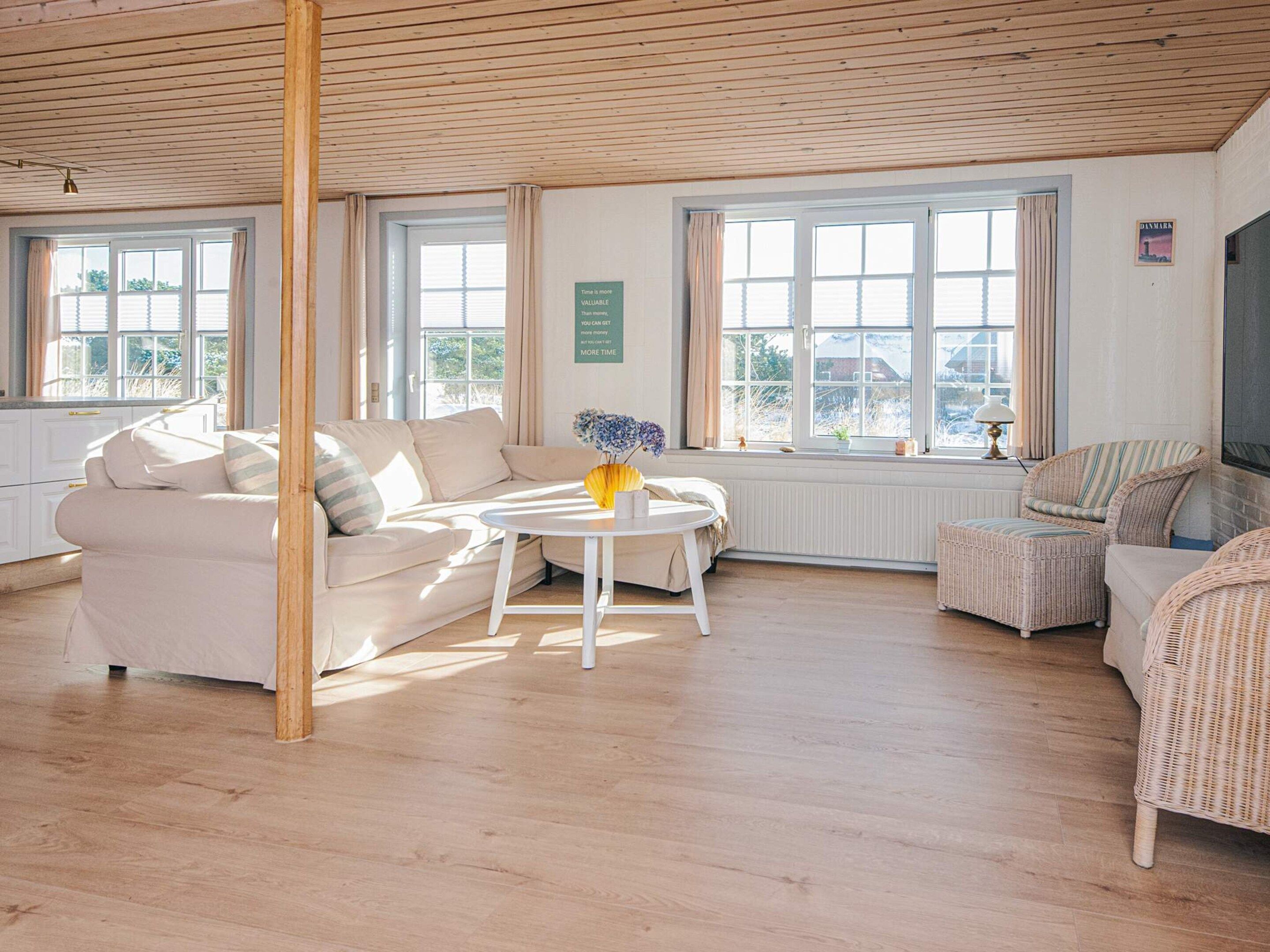 A bright room with a sofa, a round table, and wicker chairs.