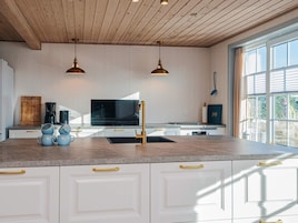A modern kitchen with white cabinets, a central island, a black stove, and two pendant lights.