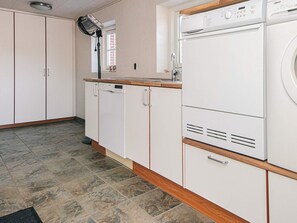 A kitchen with white cabinets, a built-in dishwasher, and a washing machine. - 6 Person Holiday Home in Blavand (Blavand)