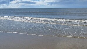 Une plage avec des vagues, un ciel dégagé et un horizon lointain.