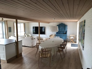 Cozy living area with a central dining table, high ceiling, and large window.