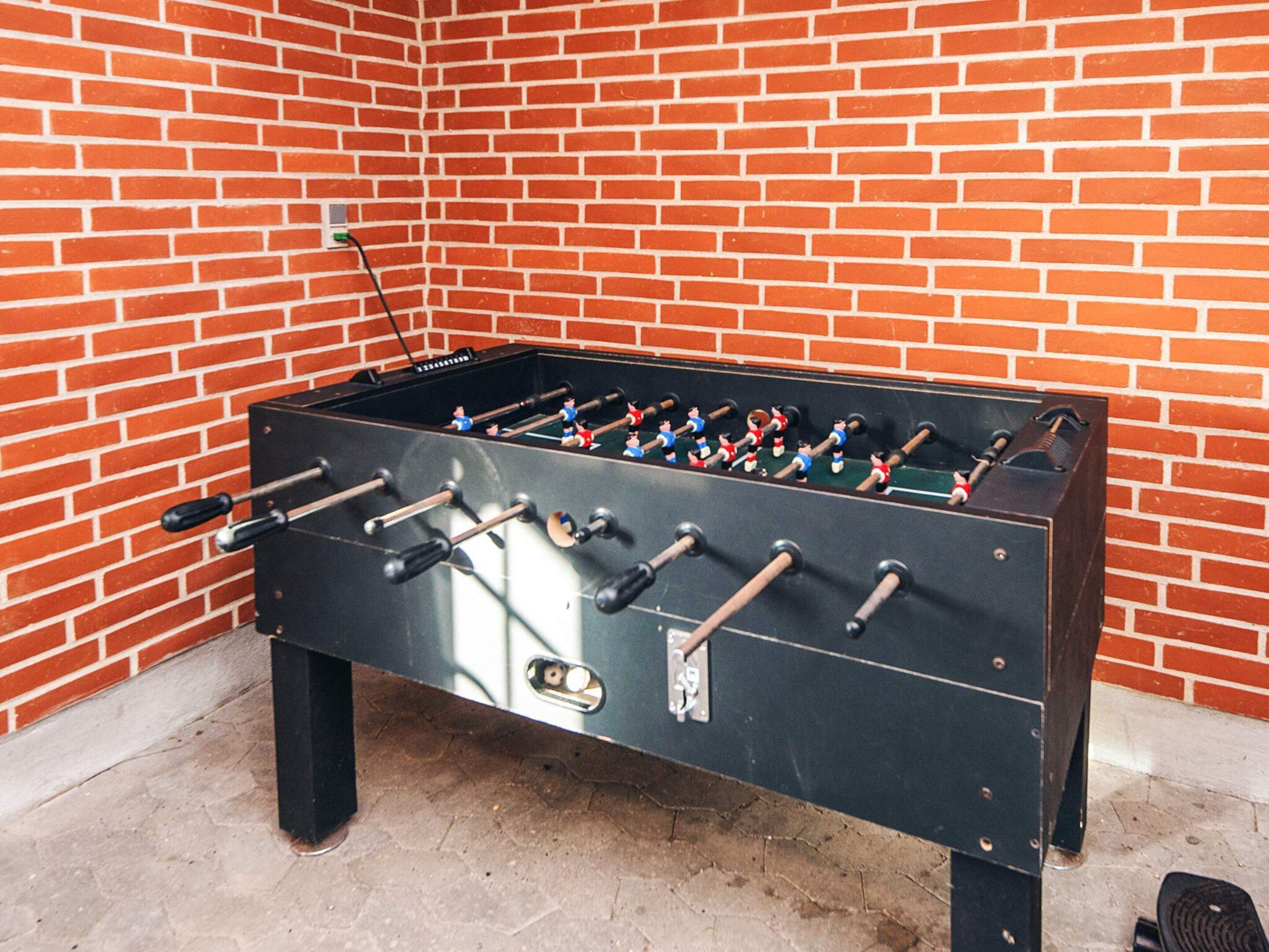 Una mesa de futbolín frente a una pared de ladrillo.