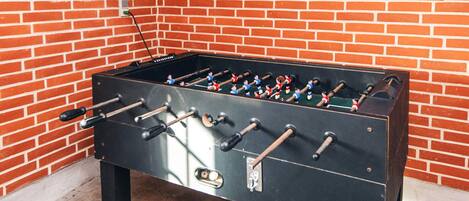 Una mesa de futbolín frente a una pared de ladrillo.