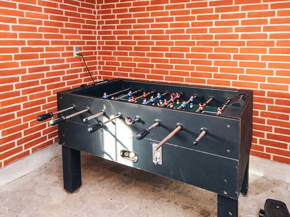 Une table de baby-foot adossée à un mur de briques.