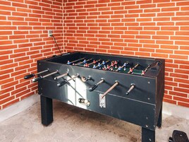 A foosball table against a brick wall.