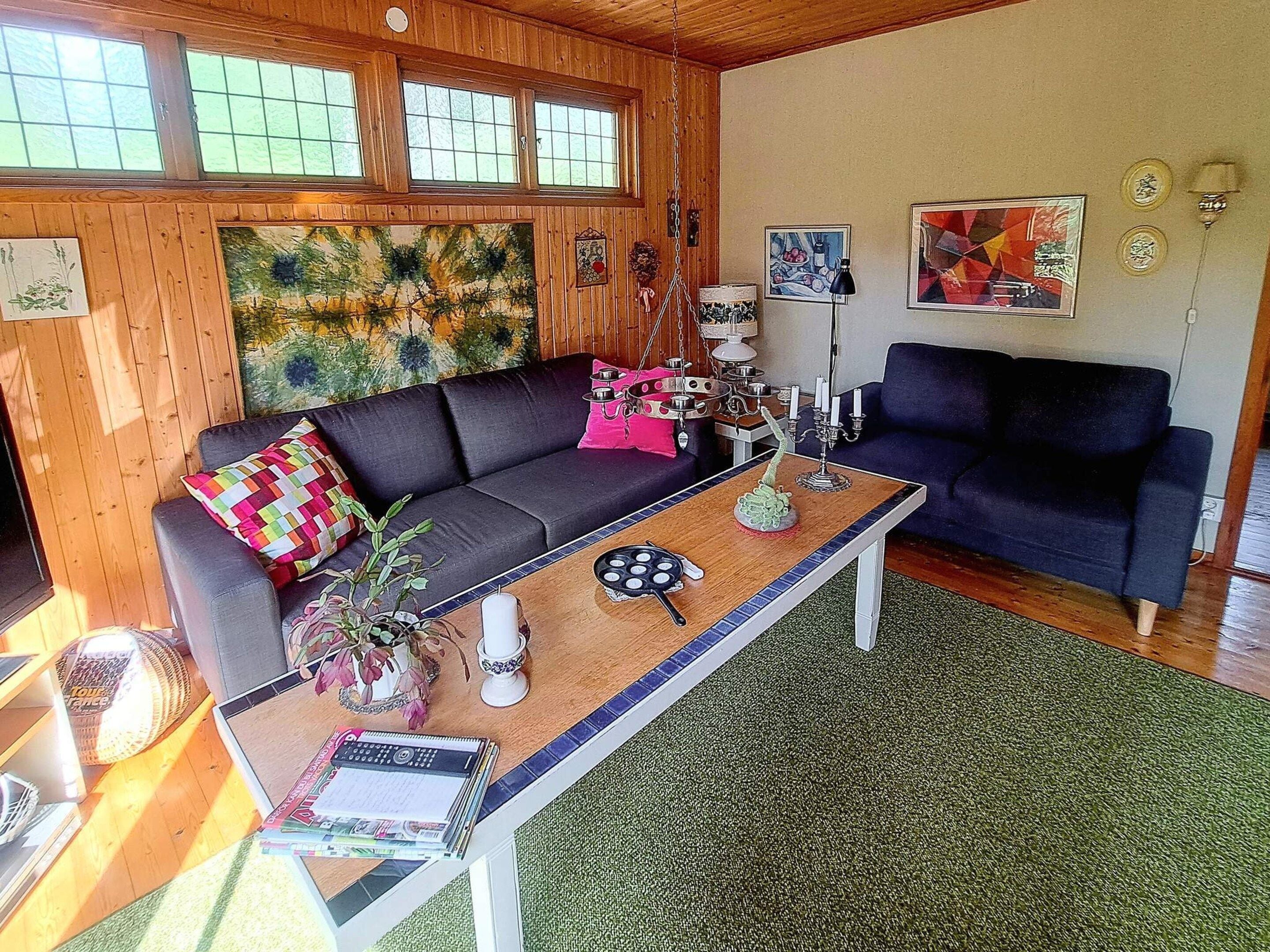 A cozy living room with a dark sofa, a coffee table, and a painting on the wall.